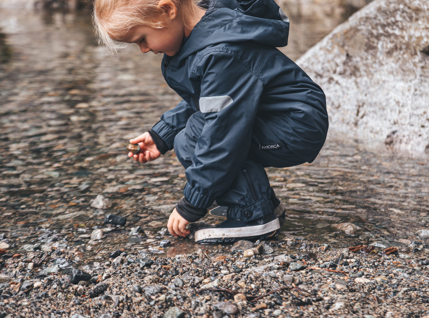 Child splashing in navy rain boots with above-knee waders by KidORCA