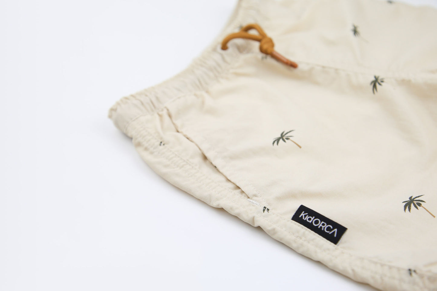 Elastic waistband detail on palm almond boys swim trunks