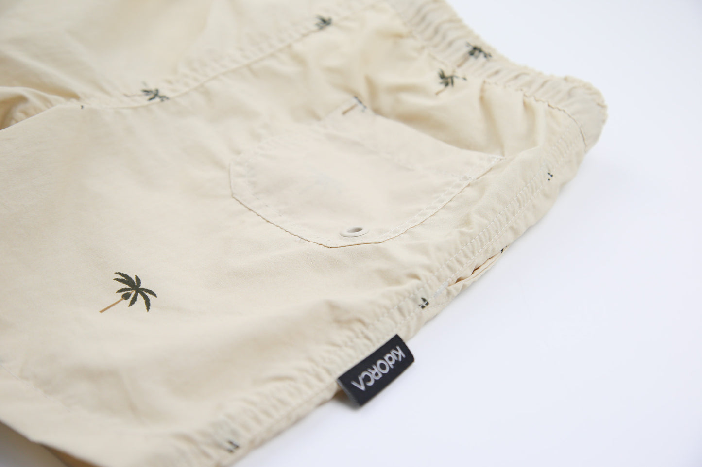Close-up of quick-dry recycled nylon fabric – palm almond swim trunks