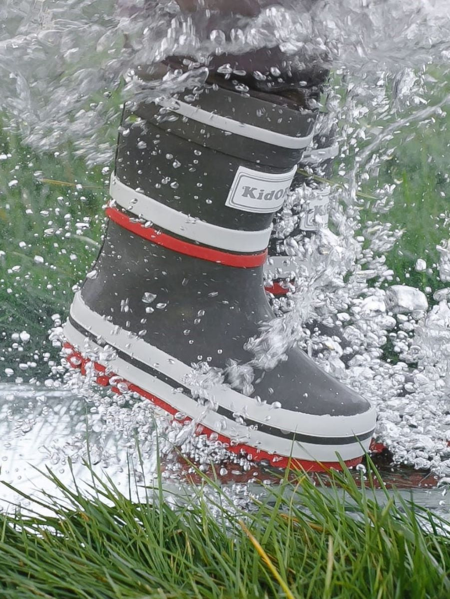 Child splashing in grey rain boots with above-knee waders by KidORCA