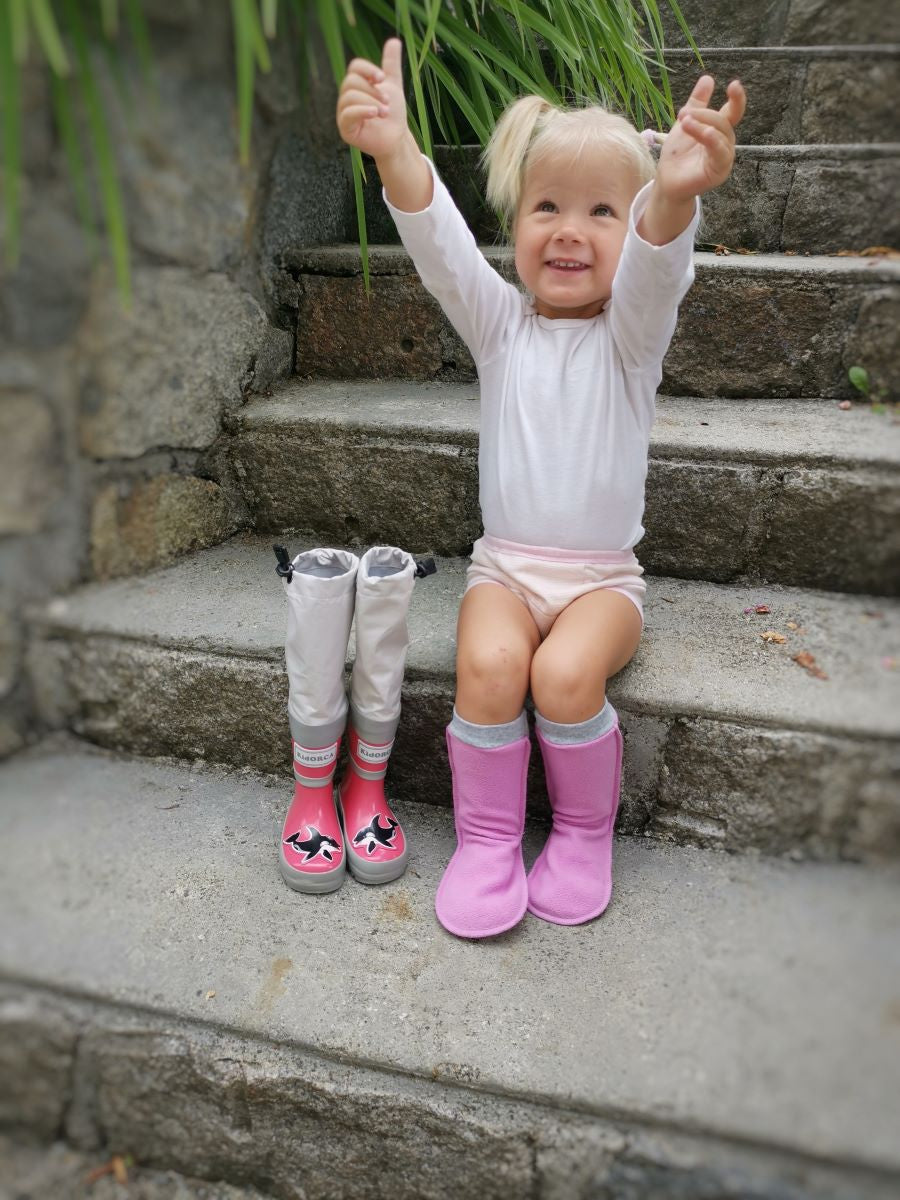 Child wearing pink above-knee rain waders – side view