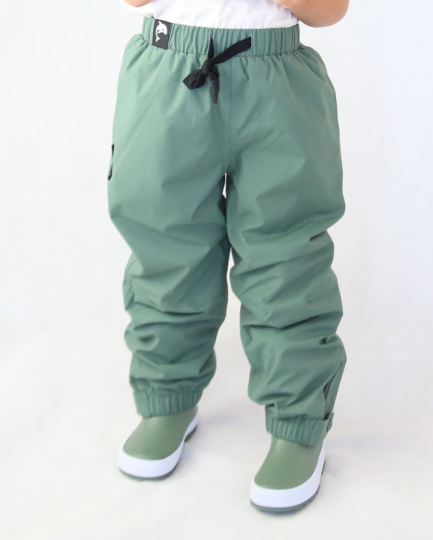 Child wearing olive hard‑shell rain pants by KidORCA