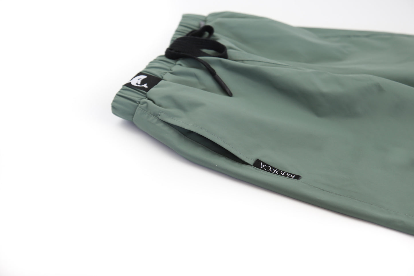 Elastic waistband detail – olive hard‑shell rain pants