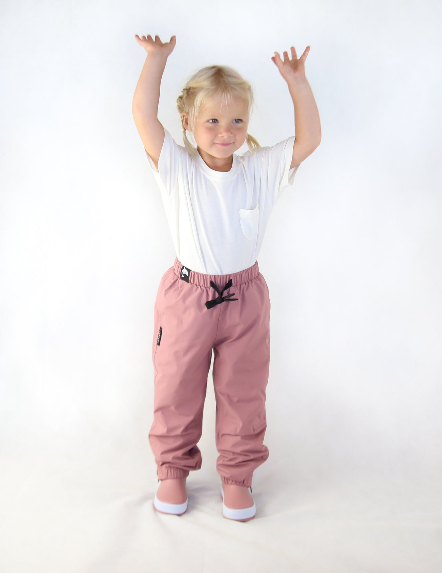 Child wearing ash-rose waterproof rain pants by KidORCA