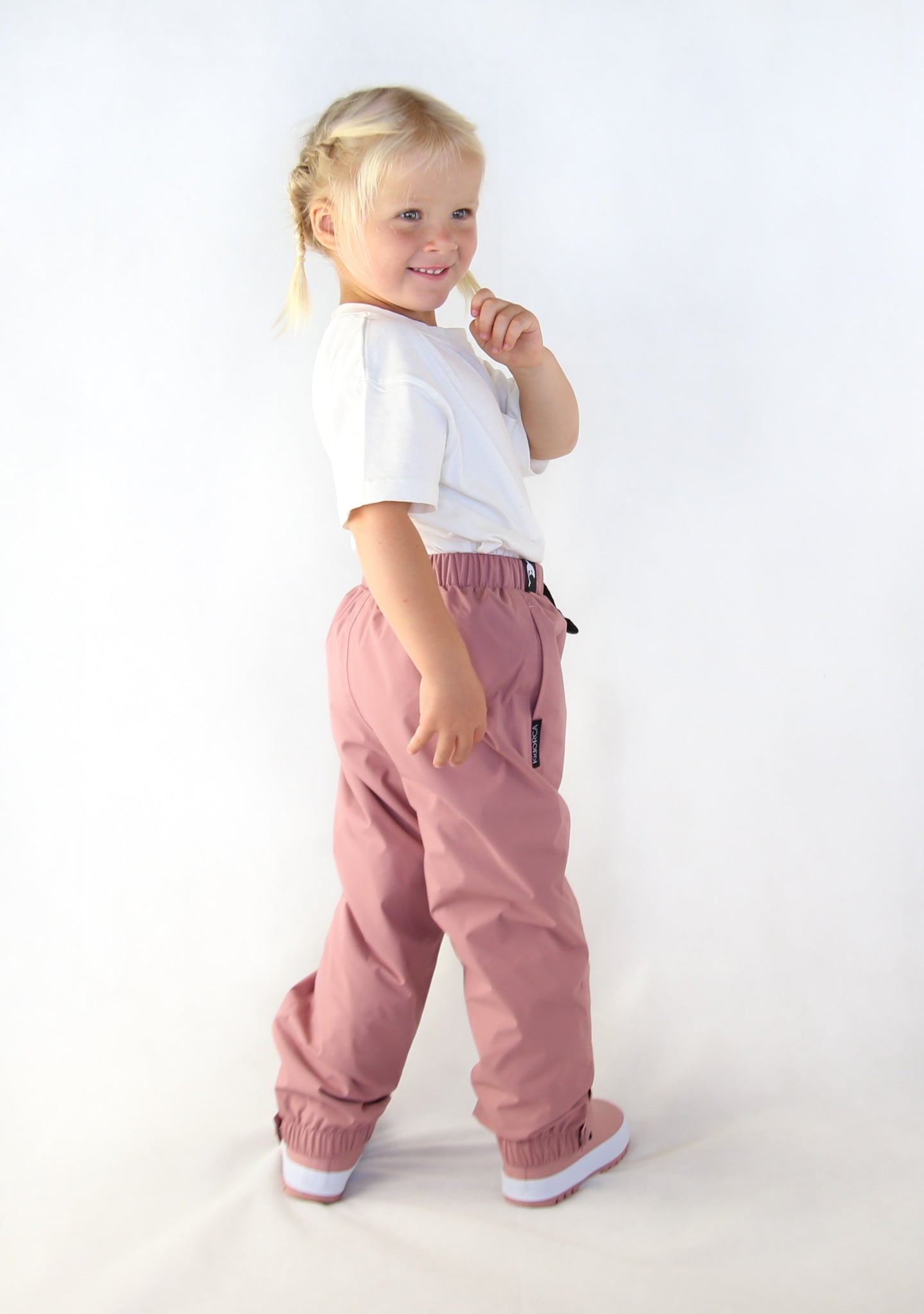 Child wearing ash-rose waterproof rain pants by KidORCA