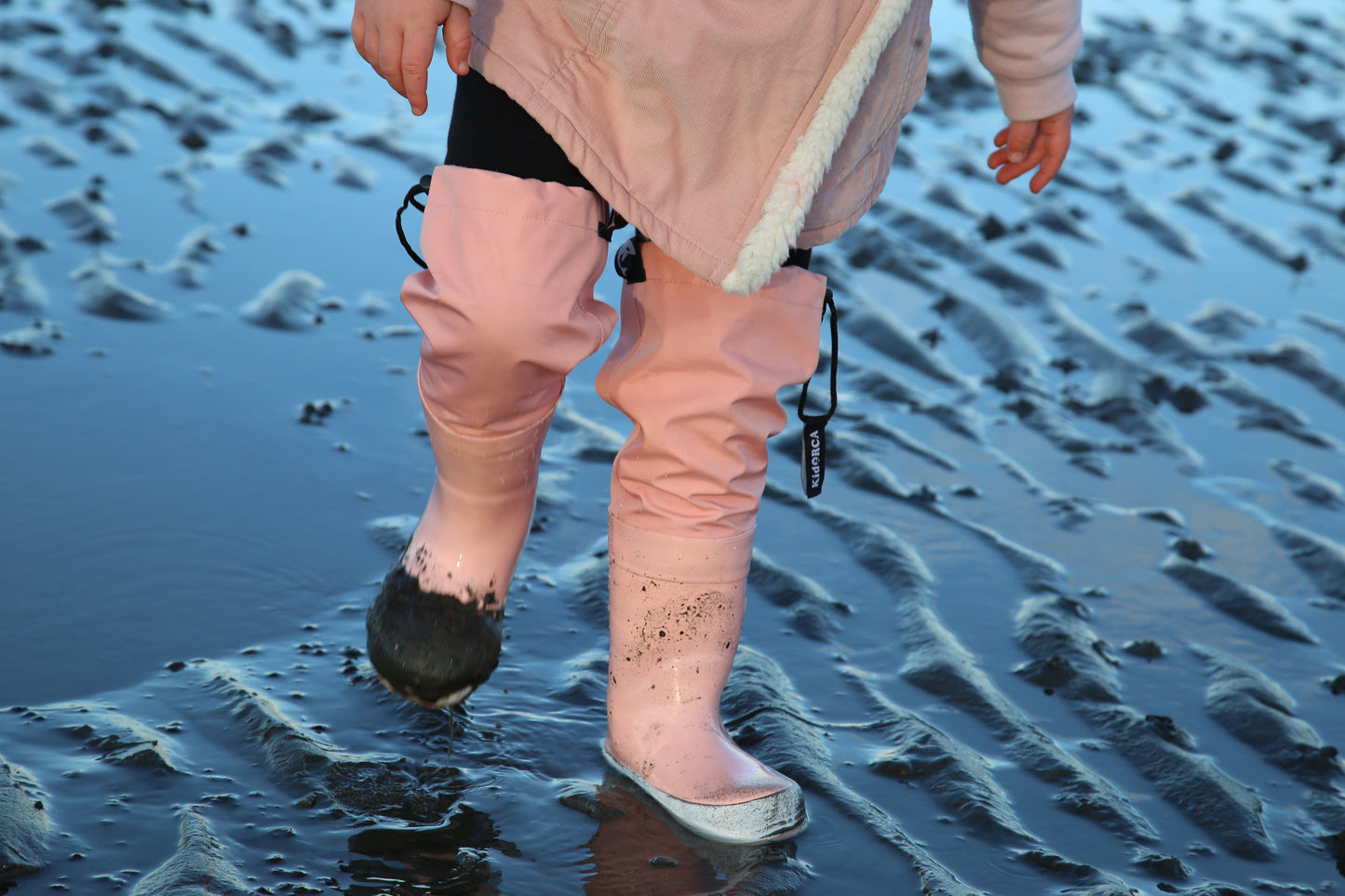 Child wearing coral above-knee rain waders – side view