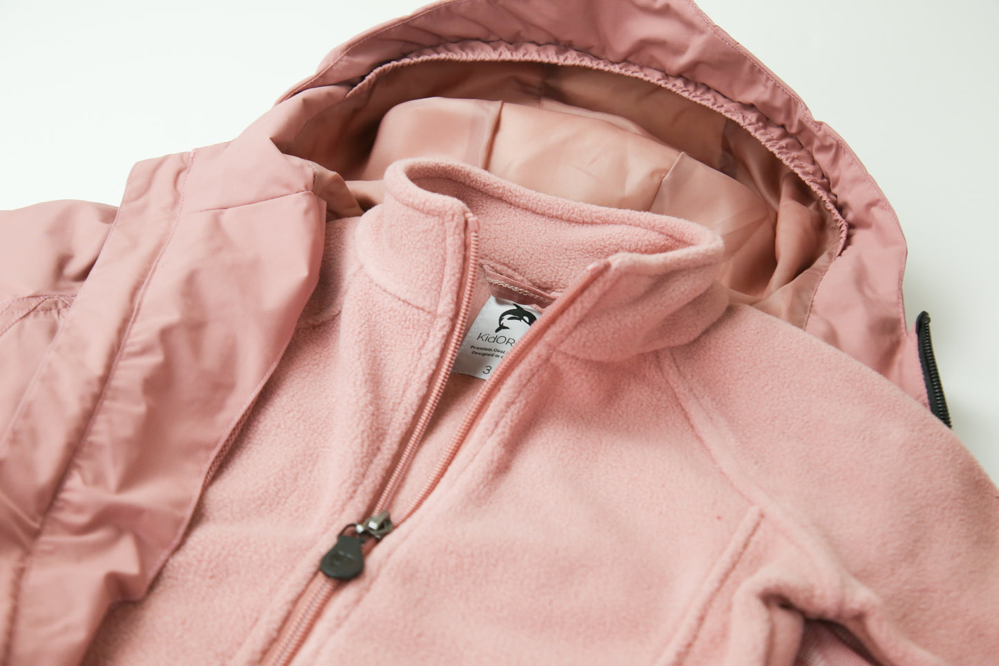 Close-up of waterproof zipper and high collar – ash‑rose rain jacket